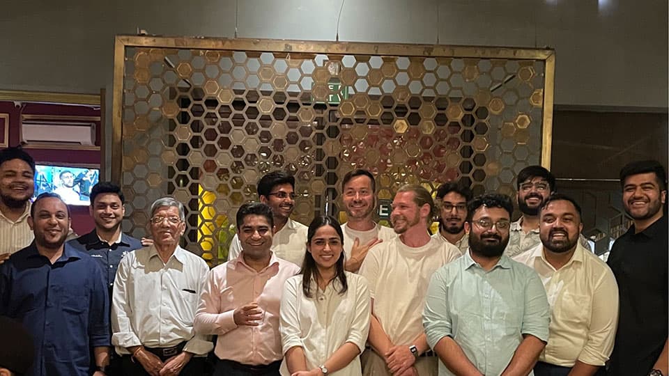 13 alumni standing with Ben Cole in Delhi at The Imperial Spice restaurant. They are standing together and smiling.